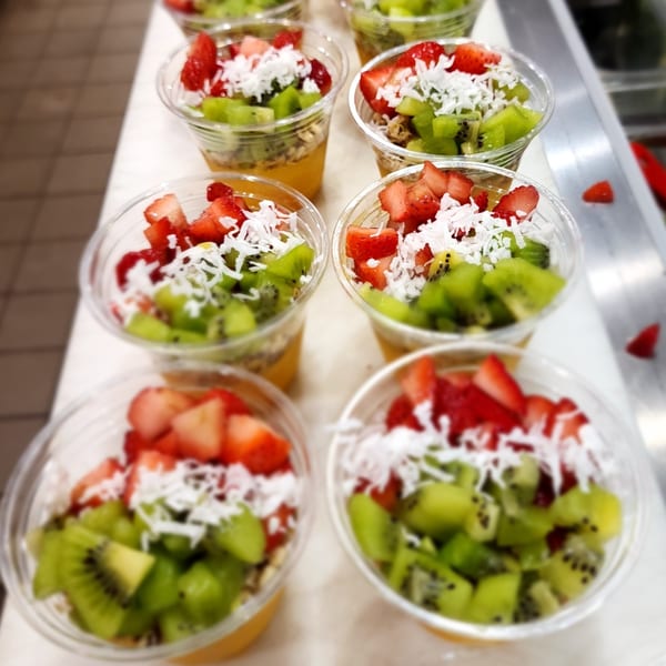 Multiple Daily Veg vegan fruit parfaits with strawberries, kiwi, and shredded coconut in clear cups.