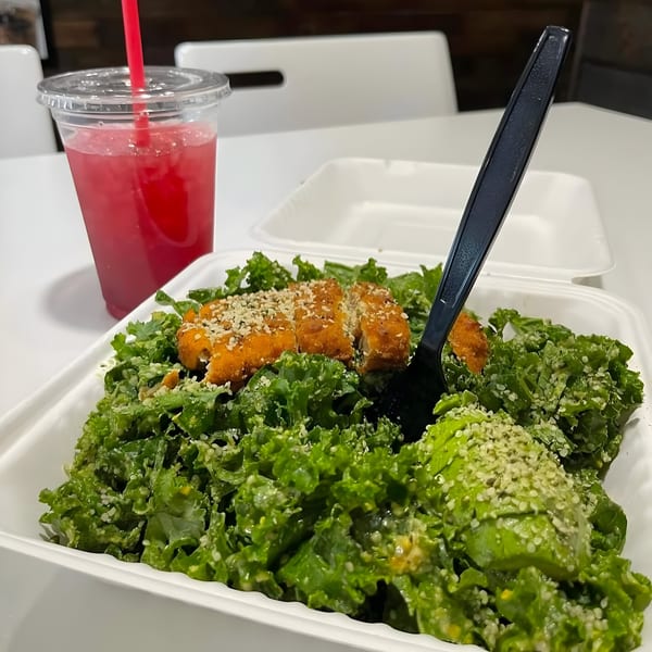 Daily Veg's vegan chicken Caesar salad with avocado, hemp seeds, and a pink drink.