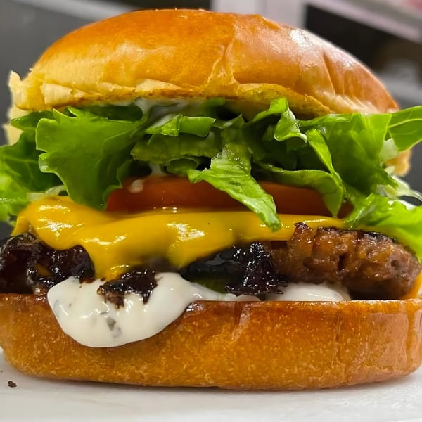 A vegan burger from Daily Veg with a patty, melted cheese, lettuce, tomato, and sauces.