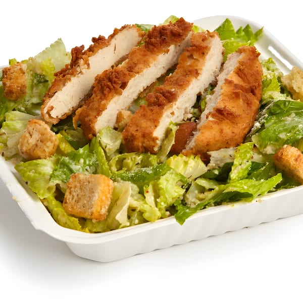 Vegan Caesar salad with crispy plant-based chicken strips and croutons in a white container.